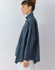 Side profile of the Ashin Shirt in Stone Blue highlighting the architectural asymmetric hem.