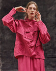 A lifestyle image of a model wearing the Yaccomaricard 1023998 Shibo top in Dust Rose, showcasing a contemporary, tonal Japanese-inspired aesthetic.